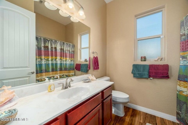 bathroom with hardwood / wood-style flooring, vanity, a wealth of natural light, and toilet