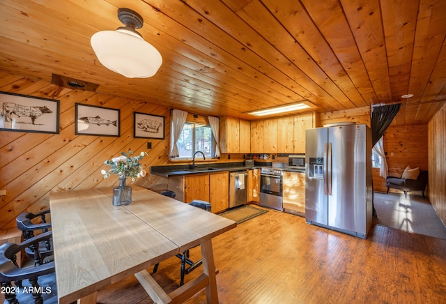 kitchen featuring wooden ceiling, stainless steel appliances, wood walls, light wood-type flooring, and dark countertops