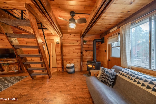 interior space with a wealth of natural light, wood ceiling, a wood stove, and wood finished floors