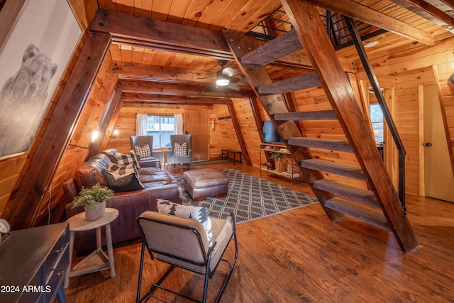 living room with wooden ceiling, wood walls, wood finished floors, and beamed ceiling