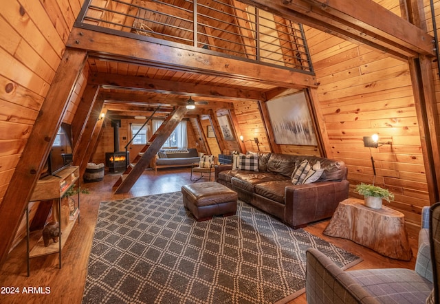 living area with beamed ceiling, wood finished floors, a wood stove, wood walls, and high vaulted ceiling