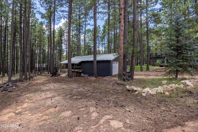 exterior space featuring a garage, metal roof, and an outdoor structure