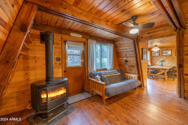 bedroom with wooden ceiling, wood finished floors, a wood stove, wood walls, and beam ceiling