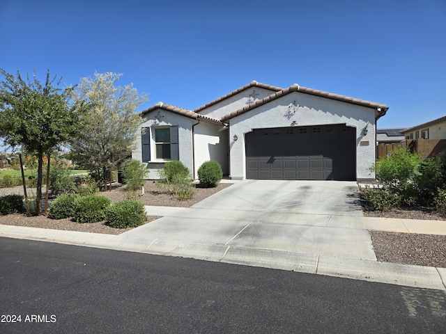 mediterranean / spanish-style home with driveway, an attached garage, a tile roof, and stucco siding