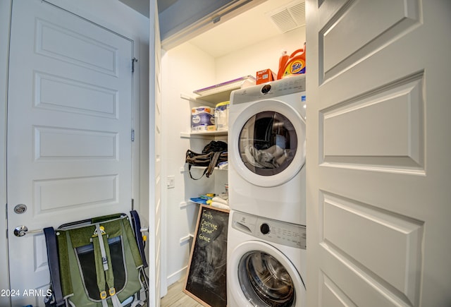 laundry area with hardwood / wood-style flooring and stacked washer / drying machine