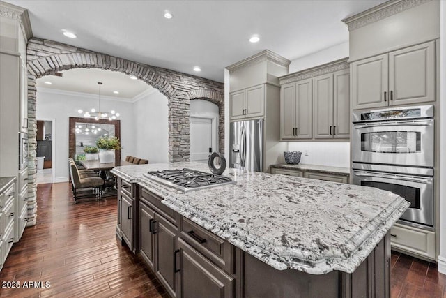 kitchen featuring an inviting chandelier, arched walkways, decorative columns, and stainless steel appliances