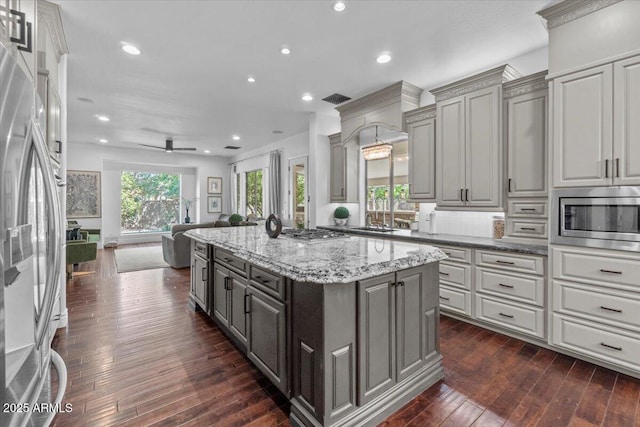 kitchen with gray cabinets, a kitchen island, dark wood-style flooring, open floor plan, and stainless steel appliances