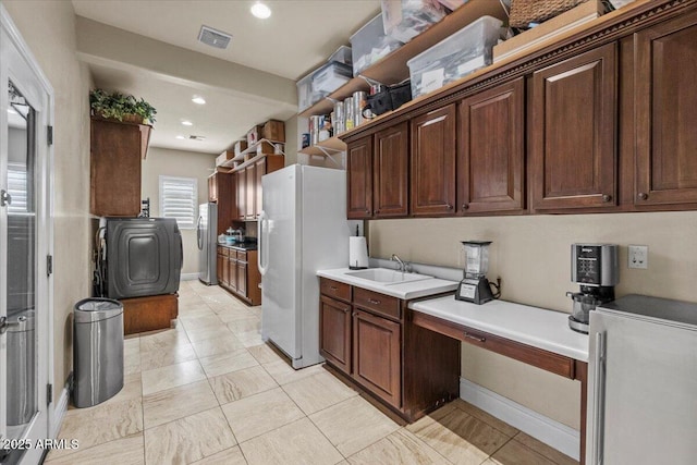 kitchen with visible vents, freestanding refrigerator, a sink, and light countertops