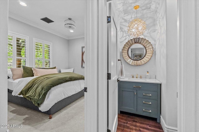 bedroom with visible vents, ornamental molding, dark wood-style floors, a chandelier, and a sink