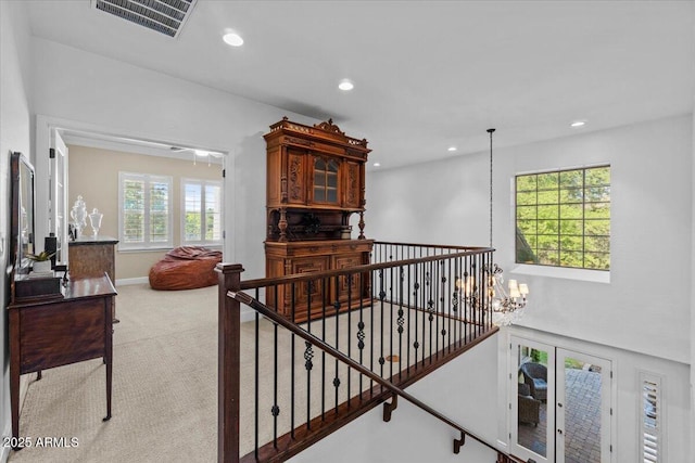 corridor featuring an upstairs landing, carpet flooring, recessed lighting, and a chandelier
