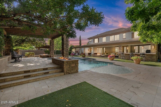 pool at dusk featuring an outdoor living space with a fire pit, a patio area, and an outdoor pool