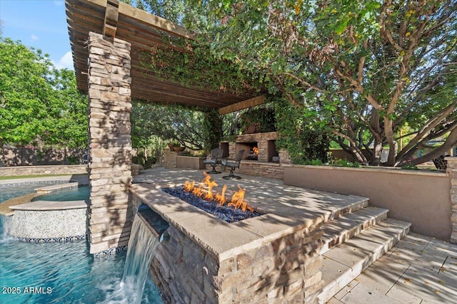 view of patio / terrace with a fire pit, an outdoor stone fireplace, and an outdoor pool