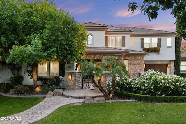 multi unit property featuring a garage, stucco siding, a front lawn, and stone siding