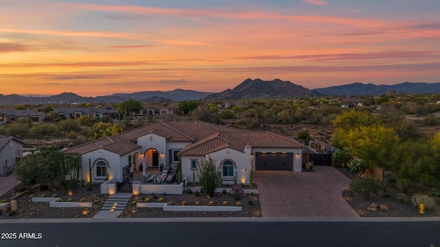 mediterranean / spanish house featuring a tile roof, a mountain view, an attached garage, driveway, and stucco siding