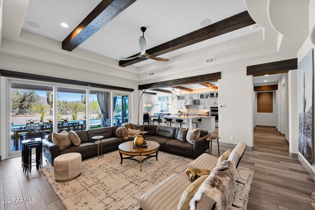 living room with ceiling fan, beam ceiling, light wood finished floors, and baseboards