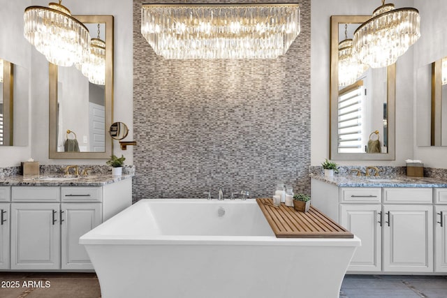 full bath with a chandelier, a soaking tub, and two vanities