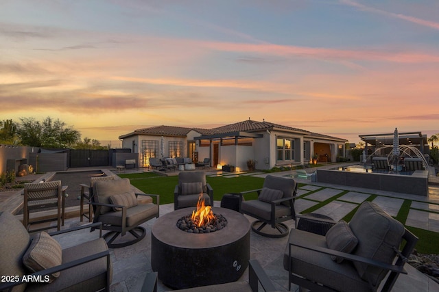 back of house featuring an outdoor living space with a fire pit, a tile roof, a patio, and stucco siding