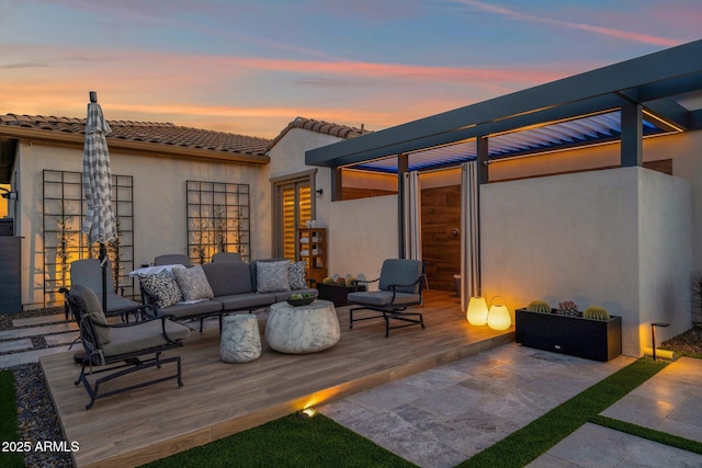 back of property at dusk featuring a deck, an outdoor hangout area, stucco siding, and a tile roof