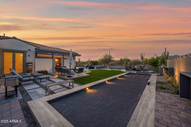 pool at dusk featuring a game area, an outdoor living space, fence, and central AC