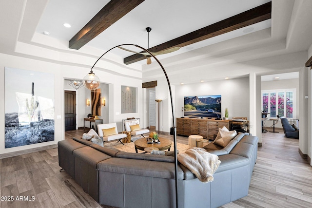 living room with a raised ceiling, light wood-style flooring, and beam ceiling