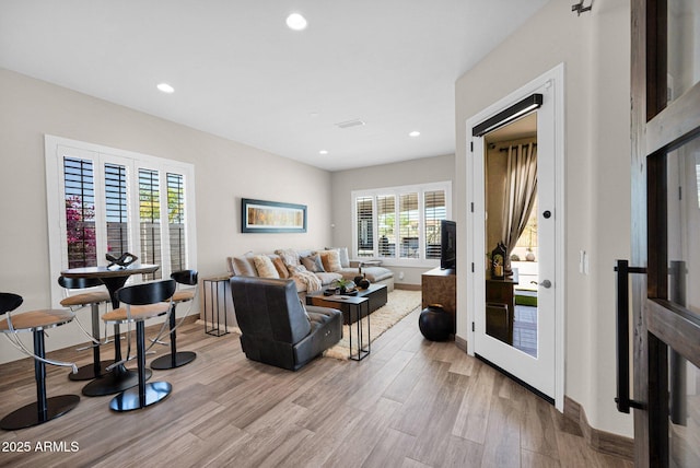 living room with light wood finished floors, recessed lighting, and baseboards