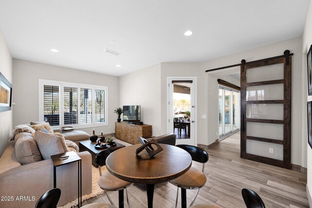 living room with light wood-style floors, a barn door, recessed lighting, and baseboards
