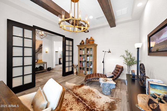 sitting room featuring a chandelier, beamed ceiling, wood finished floors, and french doors