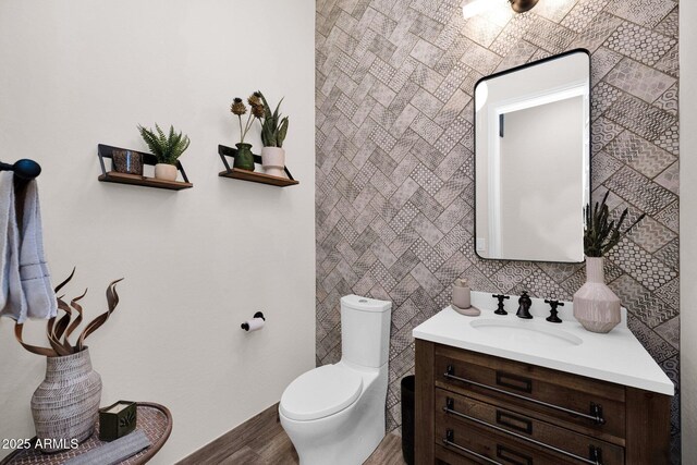 bathroom featuring wood finished floors, toilet, vanity, and baseboards