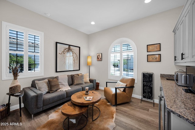 living room with wood finished floors, baseboards, and recessed lighting