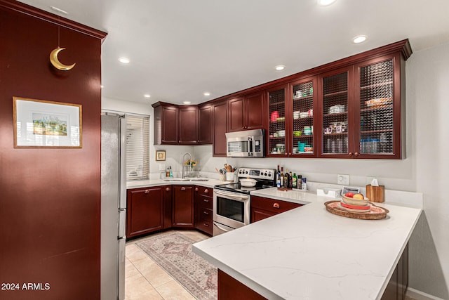 kitchen featuring stainless steel appliances, sink, kitchen peninsula, light stone countertops, and light tile patterned floors