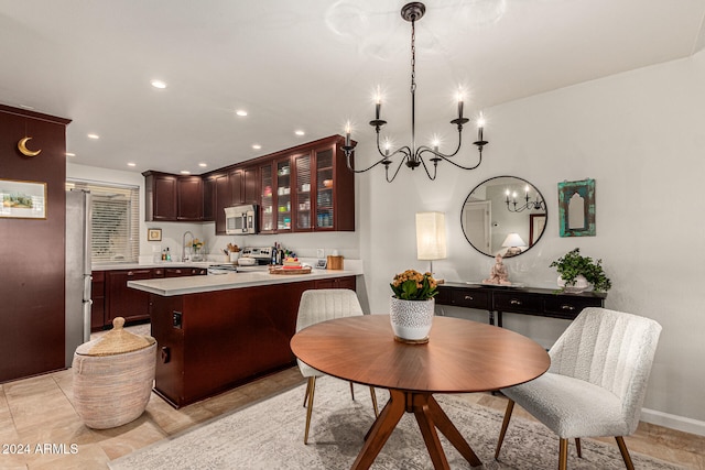 kitchen featuring appliances with stainless steel finishes, dark brown cabinets, hanging light fixtures, a breakfast bar, and a chandelier