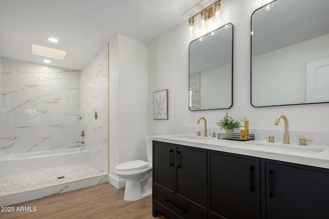 bathroom with toilet, wood finished floors, walk in shower, and a sink