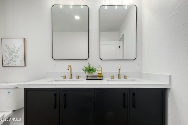 bathroom with a sink, toilet, and double vanity