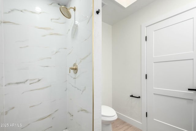 bathroom featuring a marble finish shower, toilet, baseboards, and wood finished floors