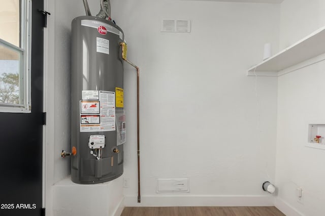 utility room featuring water heater and visible vents