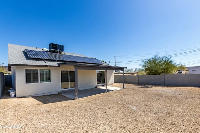 back of house featuring a fenced backyard, stucco siding, central air condition unit, a patio area, and roof mounted solar panels