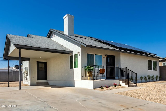 view of front of house featuring a shingled roof, concrete driveway, roof mounted solar panels, stucco siding, and a carport