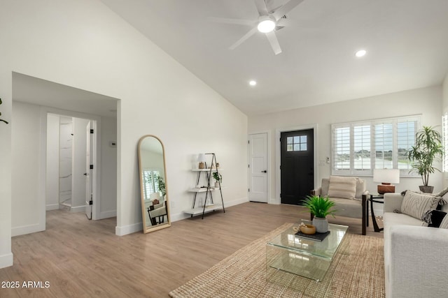 living room with baseboards, ceiling fan, high vaulted ceiling, and light wood-style floors