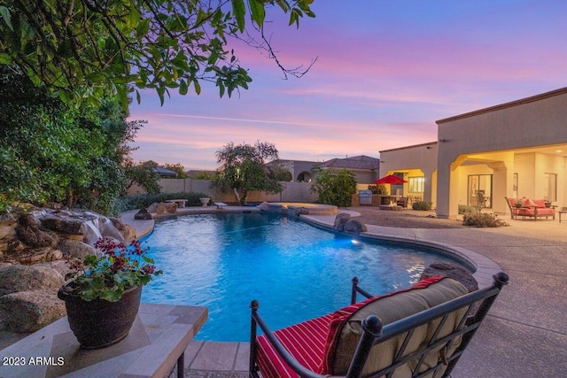 pool at dusk with an outdoor living space, a patio area, and pool water feature