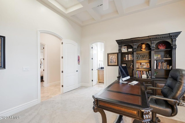 carpeted office space featuring coffered ceiling, a towering ceiling, and beamed ceiling