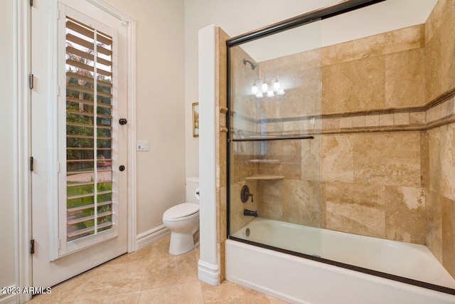 bathroom with tile patterned floors, toilet, and combined bath / shower with glass door