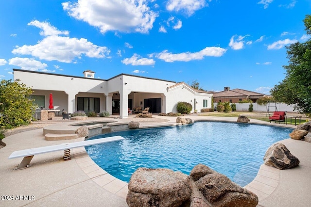 view of pool featuring a jacuzzi, a patio area, and a diving board