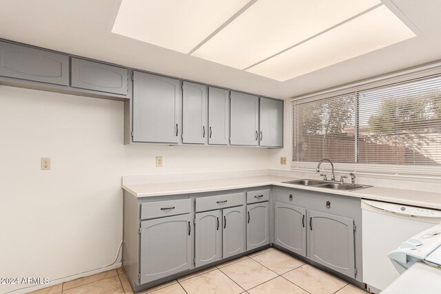 kitchen featuring light tile patterned floors, white dishwasher, gray cabinets, and sink