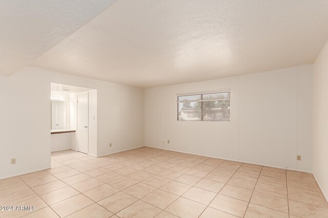 tiled spare room featuring a textured ceiling