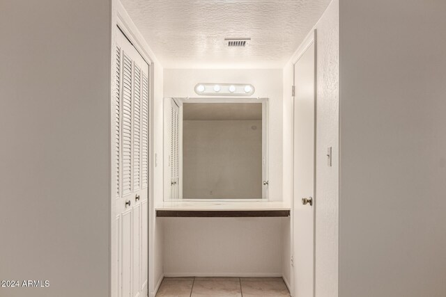 corridor featuring light tile patterned floors and a textured ceiling