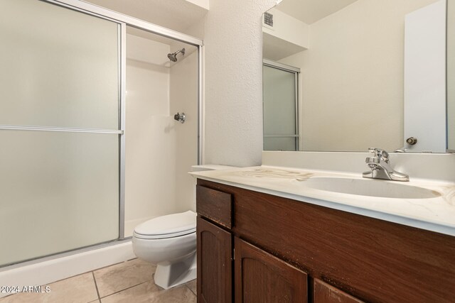 bathroom featuring tile patterned floors, vanity, a shower with shower door, and toilet