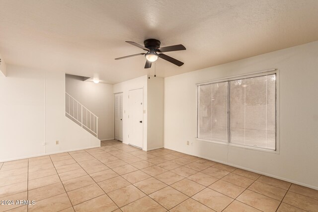 tiled empty room featuring ceiling fan