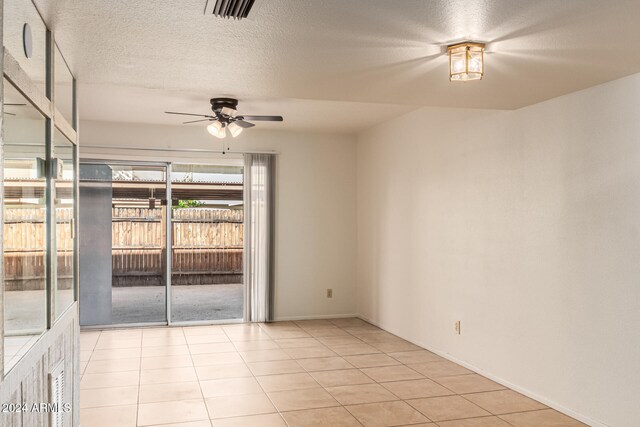 tiled empty room featuring a textured ceiling and ceiling fan