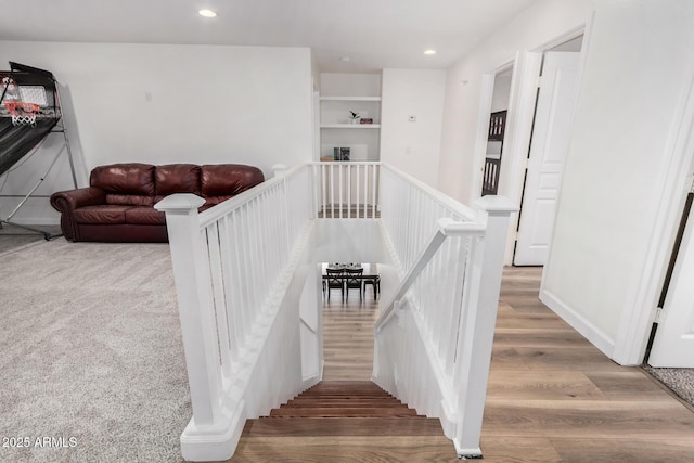 stairs with hardwood / wood-style flooring and built in shelves