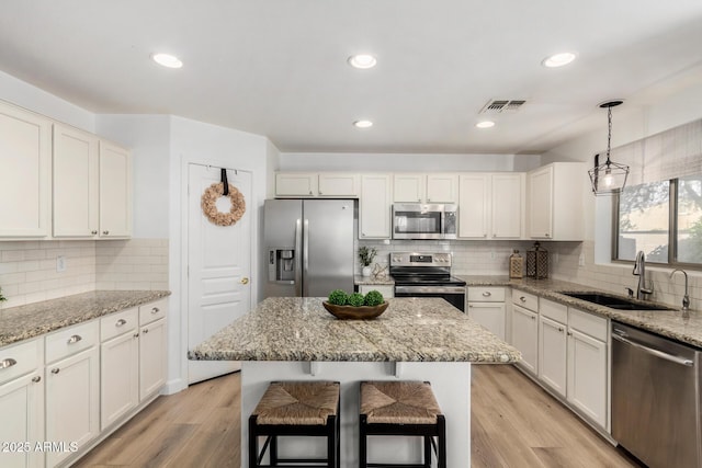 kitchen with pendant lighting, sink, a breakfast bar area, a kitchen island, and stainless steel appliances